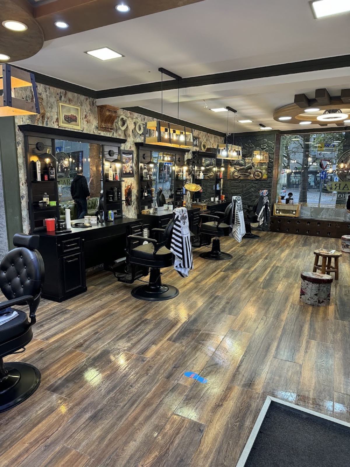 Innenraum von Oscar Barber Shop in Göppingen mit klassischen schwarzen Barberstühlen und Holzboden